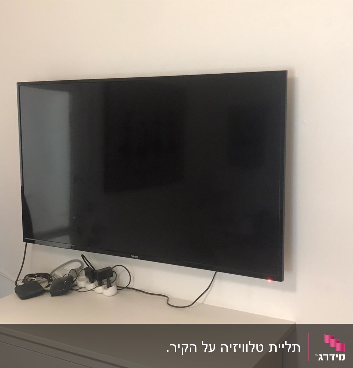 טלוויזיה תלויה על הקיר עם כבלים ומפצל חשמל